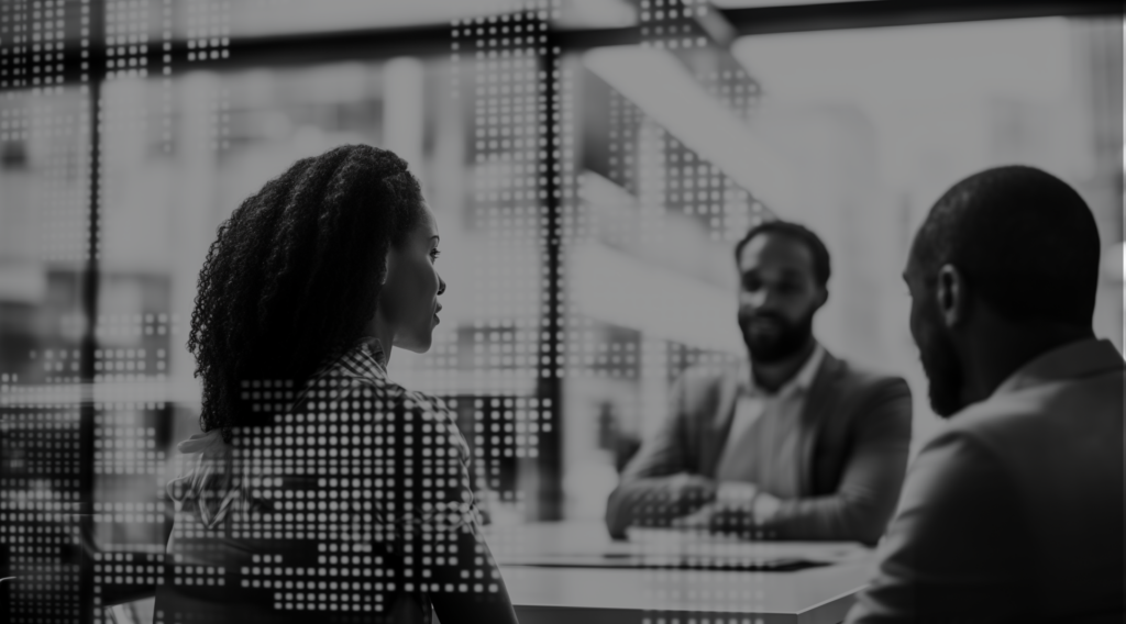 A group of three people in casual business attire, two of whom are looking away from the camera. The image is obscured by glass with patterns etched into it.